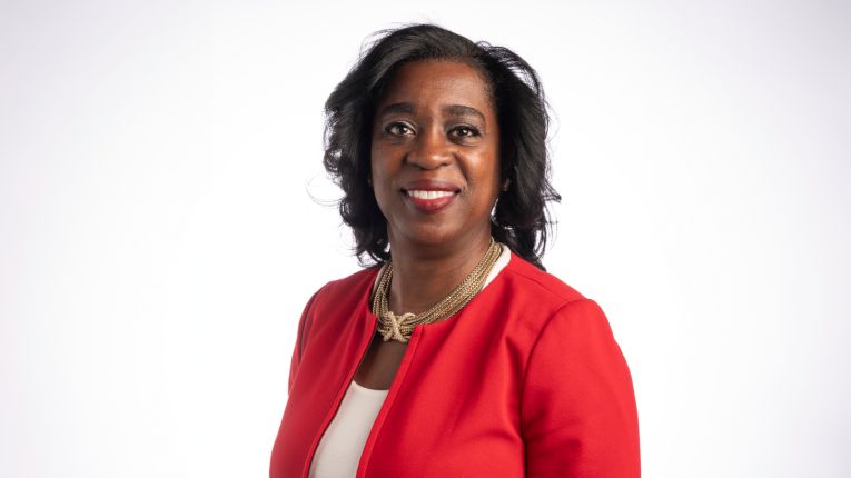 Wendy Nembhard pictured in red blazer in front of white background.
