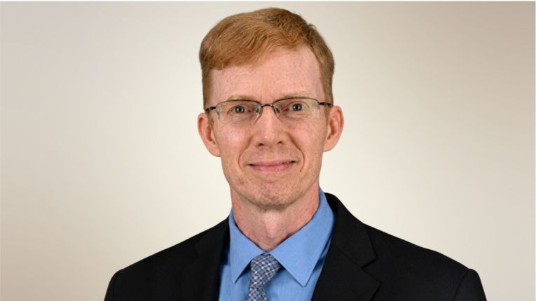 Casey Crump, MD, PhD, MPH,  professor in the Department of Family and Community Medicine at McGovern Medical School smiling in black suit and blue shirt. (Photo by UTHealth Houston)