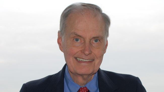 A man standing in front of a window overlooking a city