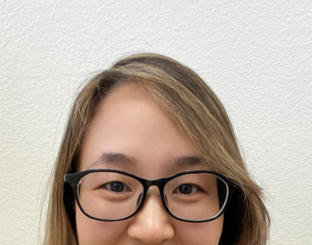 Jingjing Gao, PhD, smiling at camera wearing glasses and a maroon collard shirt.