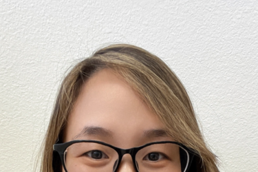 Jingjing Gao, PhD, smiling at camera wearing glasses and a maroon collard shirt.