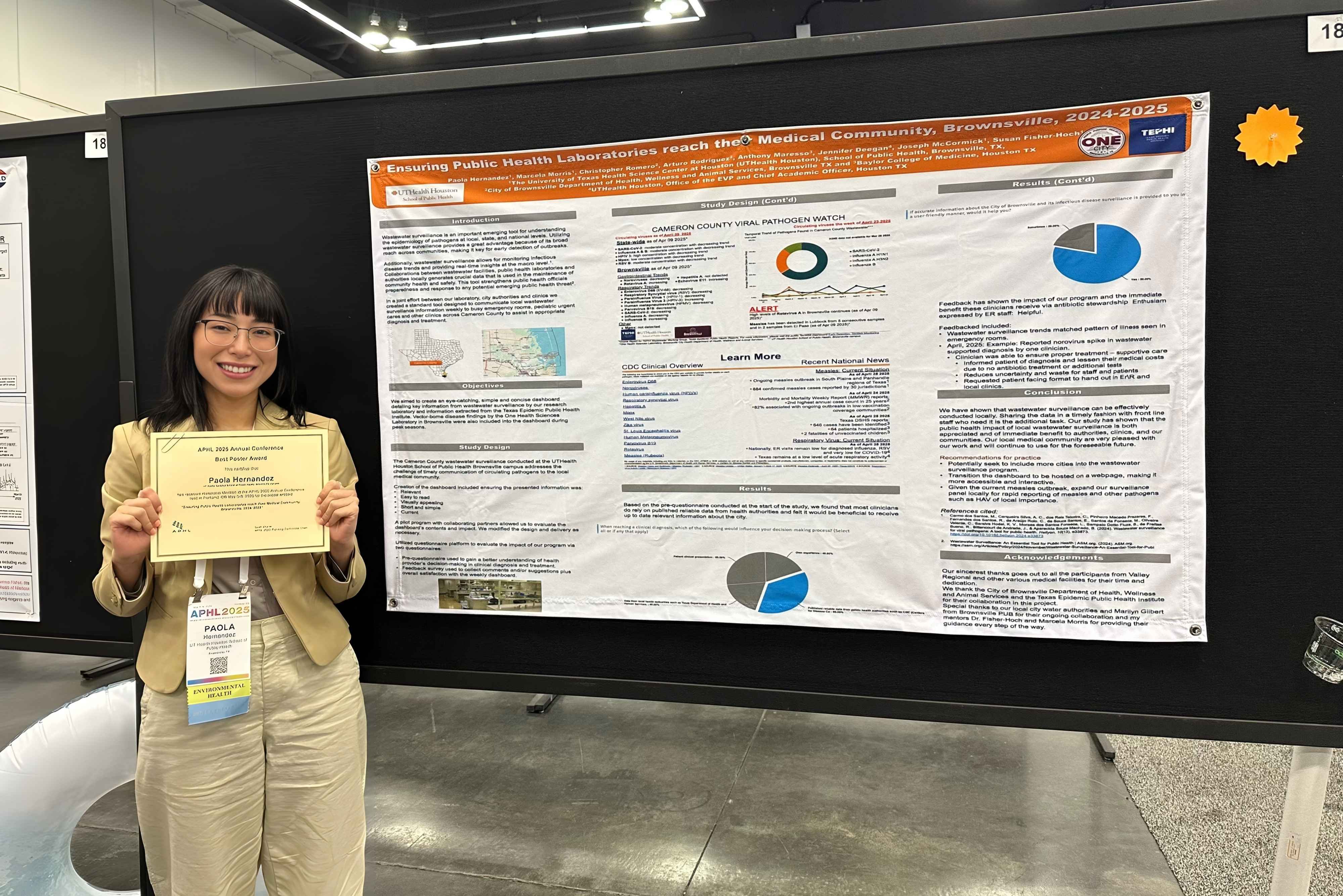 Paola Hernandez holding award certificate in front of research poster.